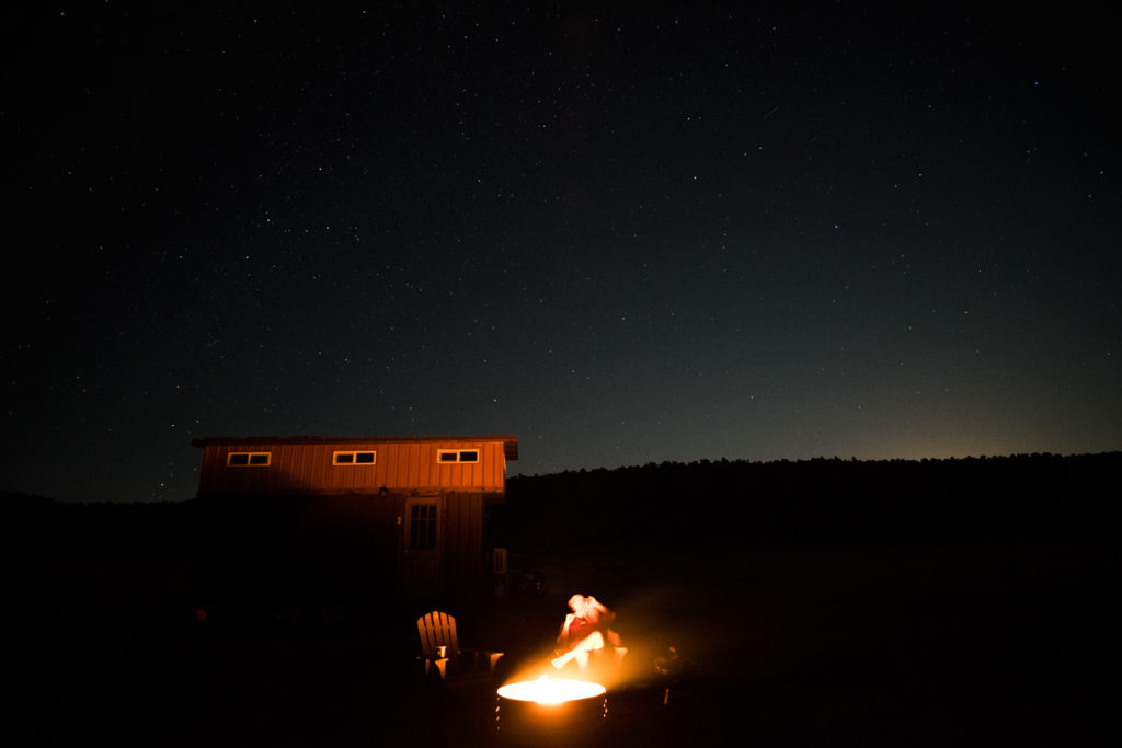 Campfire, tiny home, and some stars in the back